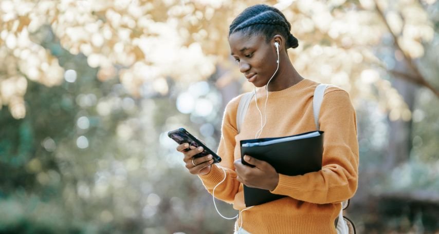 Student listening to music using smartphone in park