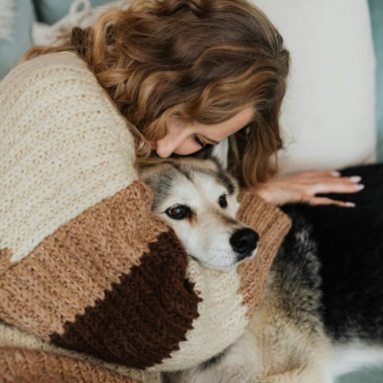 Woman Hugging a Dog While Lying on a Sofa